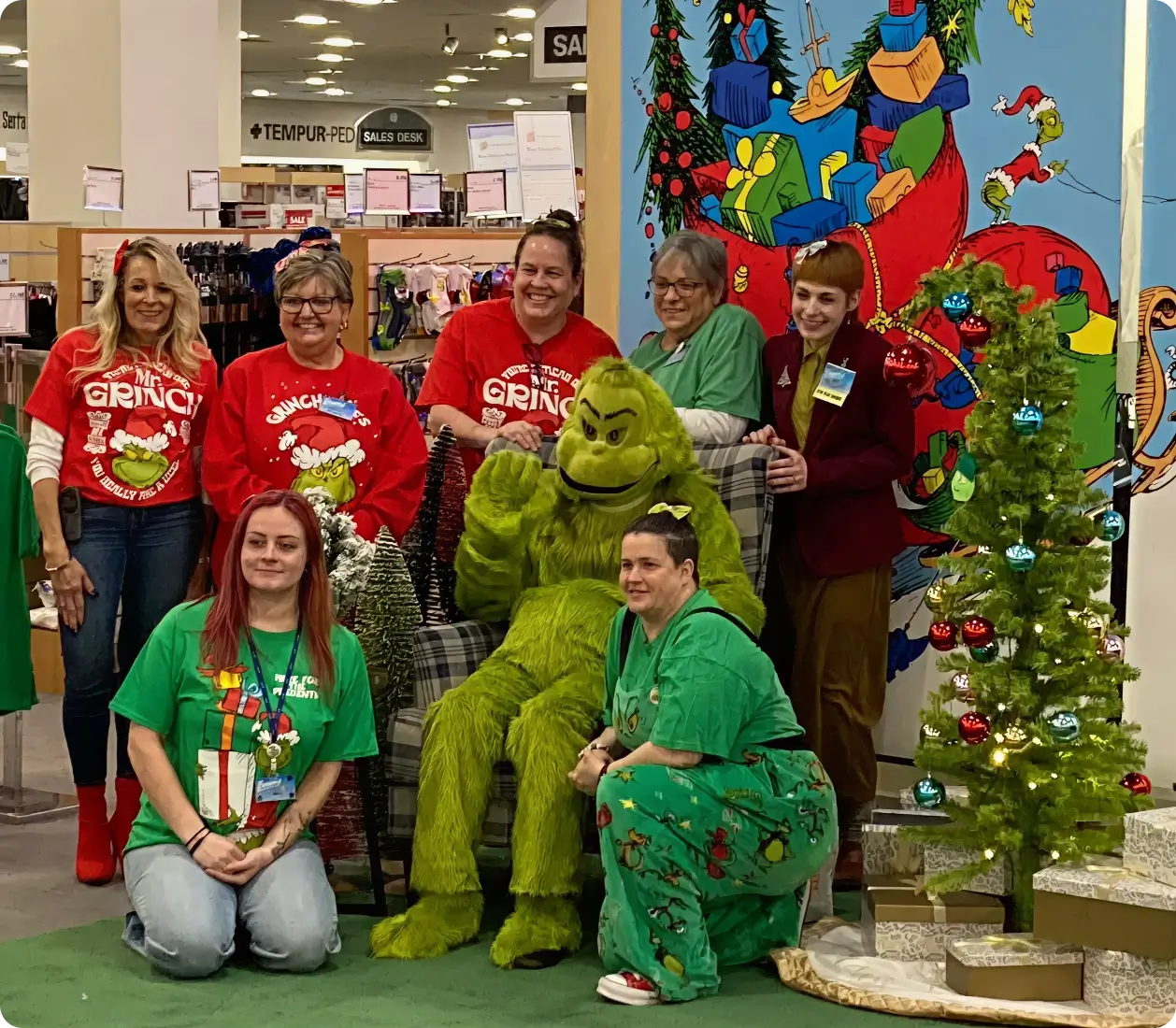 Smiling people posing with the Grinch